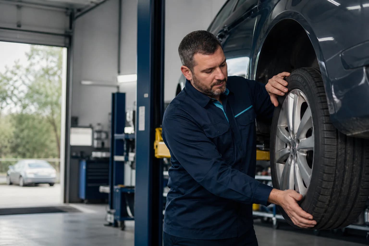 Proprietar de service auto verificând o roată într-un atelier luminos